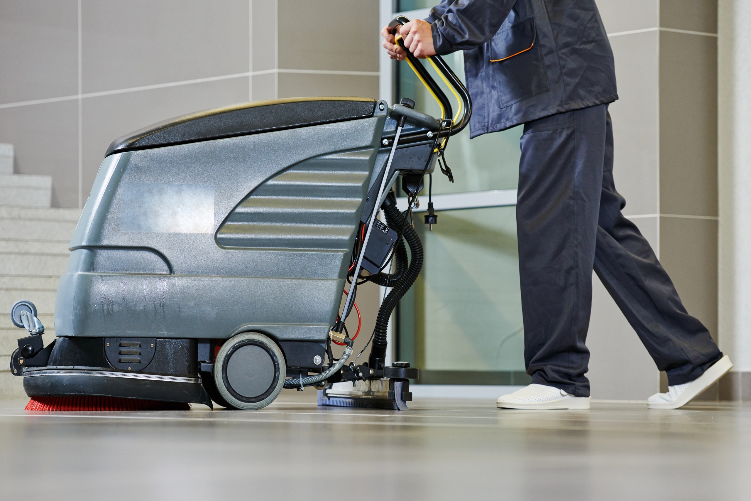 Reinigungskraft bedient Bodenreinigungsmaschine im Gebäude